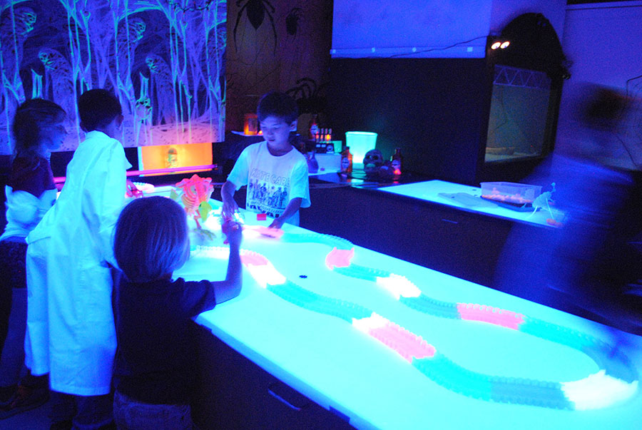kids playing at a lab table all lit up with blacklights