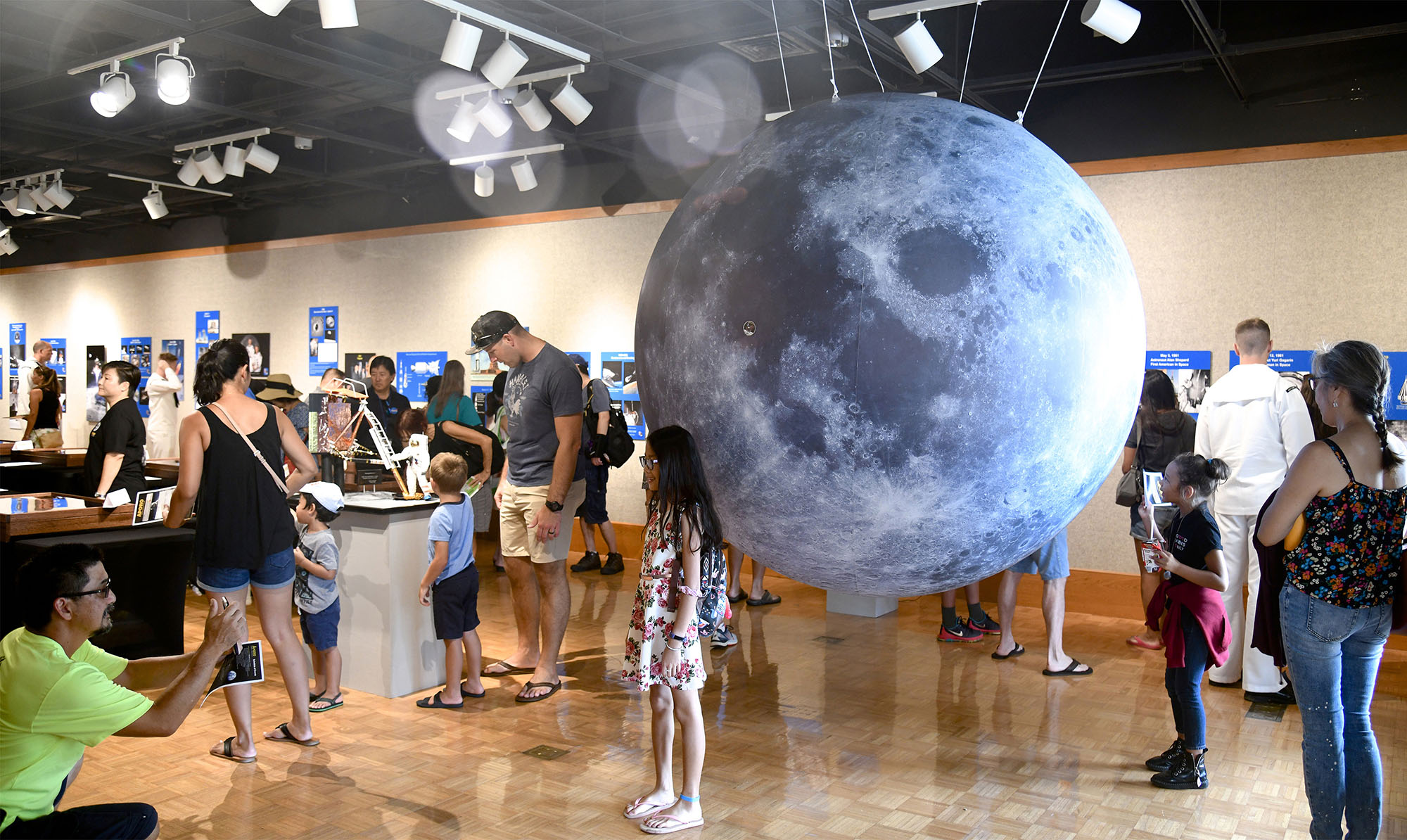 people walking around the gallery with various moon landing related exhibits