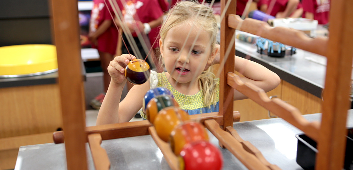 Young girl playing with Newton's cradle