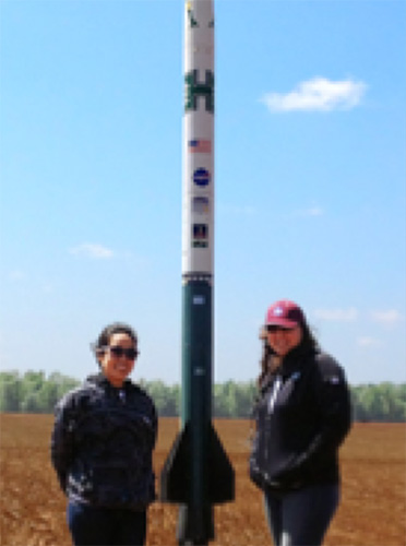 Lyra Hancock and Rose Wailehua from Windward Community College standing in front of their rocket ready for its launch.