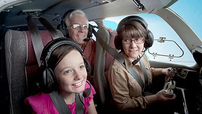 Two children in the front seat of an airplane with an adult behind them