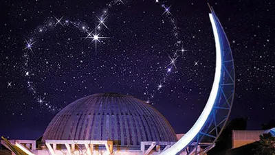 Moon sculpture lit up at night and the stars forming a heart