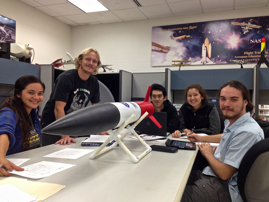 Project Imua students gathered around a table with a rocket on it